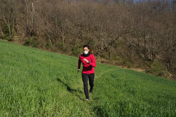 Koronavirüs salgınından dolayı yüz koruyucu maske takan genç bir kadın. Spor yapmak ve açık havada koşmak..