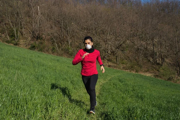 Koronavirüs salgınından dolayı yüz koruyucu maske takan sportif genç bir kadın. Fiziksel aktivite, zindelik, koşu ve açık havada dışarıda koşma..