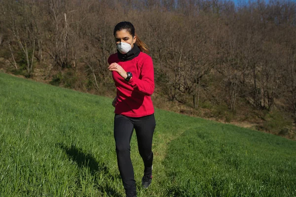 Koronavirüs salgınından dolayı yüz koruyucu maske takan genç bir kadın. Koşu, spor ve açık havada koşuyor..