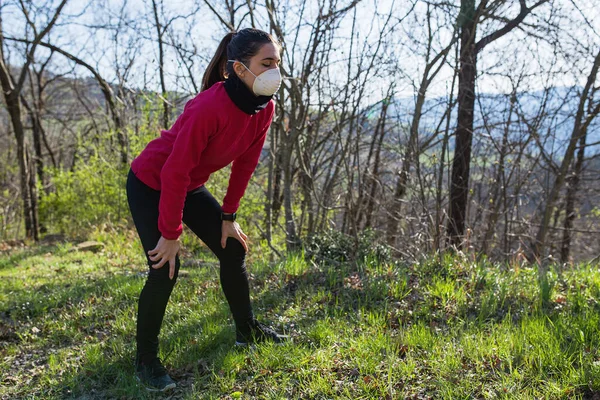 Dışarıda fiziksel aktivite uygulayan genç bir kadın. Koronavirüs sırasında koruyucu yüz maskesi takmak. Fitness, spor, koşu, sağlıklı yaşam tarzı ve salgın konsepti.