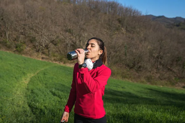 Koronavirüsle dışarıda koşan sportif kadın koruyucu maskeyle karşı karşıya. Şişede su içmek. Salgın, açık hava yaşam konsepti.