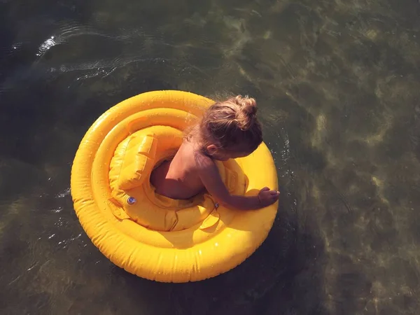 baby girl in an inflatable ring in water