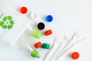 Bir sürü tek kullanımlık plastik çatal bıçak ve şişe. Beyaz zemin üzerinde plastik geri dönüşüm ve ekoloji kavramı