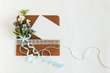 Üzerinde yabani pembe çiçekler olan bir zarf ve arka planda beyaz bir kart, Anneler Günü.