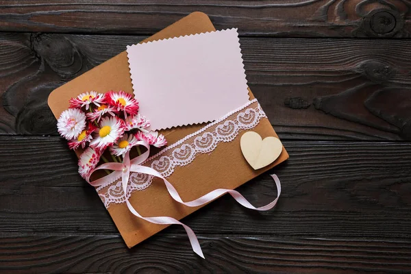 用粉红色的花和一张贺卡包裹着黑色木制背景的假日 — 图库照片