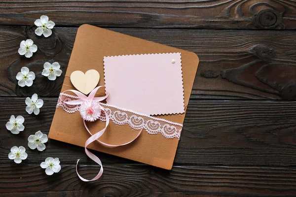 用粉红色的花和一张贺卡包裹着黑色木制背景的假日 — 图库照片