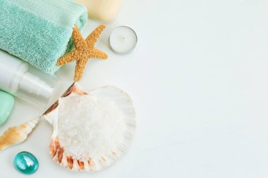 Spa kozmetik ürünleri ve üzerinde deniz yıldızları ve deniz tarağı kabuğunda tuz olan havlu.