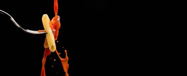 Bir domates sosu damlası çatalın üzerine düşer ve siyah arka planda makarna olur ve uzayı kopyalayabilir.