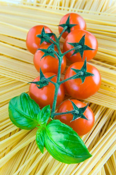 Tomato, basil, cherry tomatoes, pasta, spaghetti Vegan diet food, creative cherry tomato composition. Fresh basil, tomatoes, cooking concept, top view.