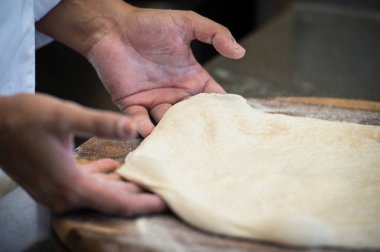 Maya unu ve su ile ev yapımı gerçek bir İtalyan pizzası hazırlamak için çeşitli aşamalarda çalışan bir pizza şefinin ellerinin ayrıntıları..