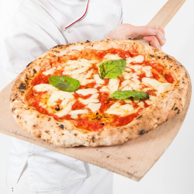 Gerçek İtalyan pizza margherita 'sının ayrıntıları mozzarella peyniri, domates, basilico pizza makinesi tahta küreğin üzerinde dinleniyor, en üstten, beyaz arka planda.