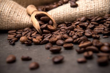 Siyah bir zeminde, kahve çekirdekleri ışık kesen cam bir fincanda İtalyan espresso kahvesi