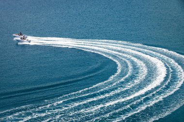 İki sürat teknesi açık denizde hızlı gider ve motoru suda bırakır.