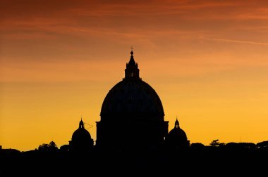 Roma 'daki San Pietro Bazilikası' nın kırmızı günbatımındaki kubbesinin çarpıcı silueti.