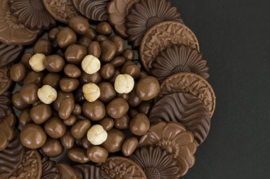 Sütlü ve sert yuvarlak çikolatalı Madlen, cam plaka üzerine dizayn edilmiş, siyah arka planda fotokopi ile. Şeker Şöleni veya herhangi bir festival kutlaması..