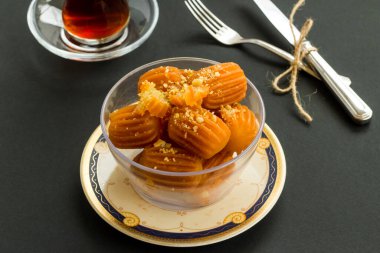 Geleneksel Türk Çıtır Tatlısı Tulumba, siyah çay üzerine doğranmış fındıkla süslenmiş. Şeker Şöleni Kavramı..