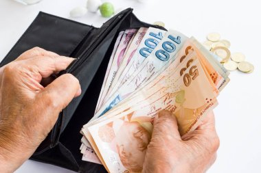 Beyaz arka planda, cüzdanda Türk Kağıt Parası 'nı tutan eski el.