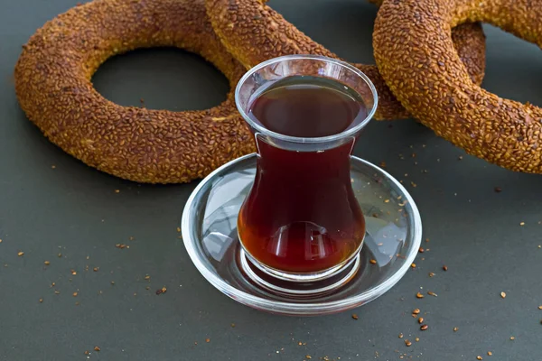 Sliced  Turkish Sesame Bagel in plate on dark surface with a glass of tea.