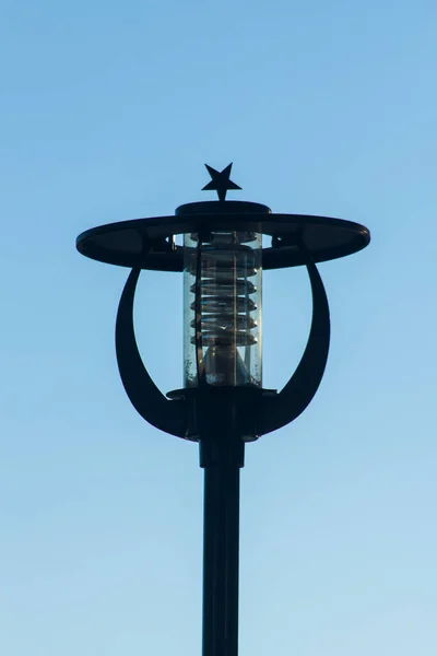 Siyah renkli. Metal ay yıldızı şeklindeki sokak lambası mavi üzerine yakın plan çekilmiş..