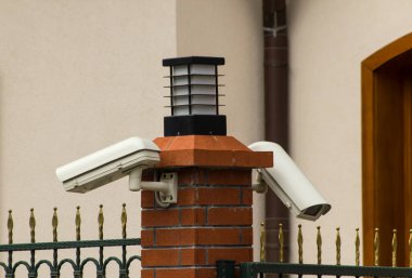 Bilinmeyen binanın önündeki çifte güvenlik kamerası. Lambalı, gün ışığında..