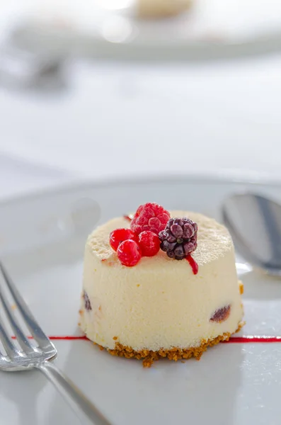 Vanilya ve Kırmızı Meyveli Tatlı Keki, beyaz bir tabakta servis edilen çatal ve kaşıkla servis edilir