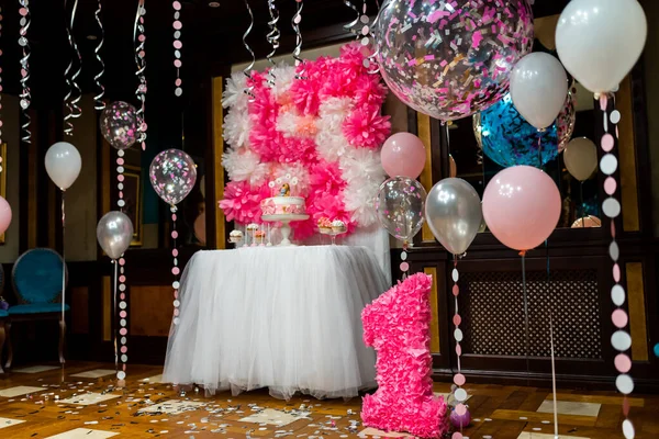 one year birthday party decoration in restaurant with balloons and cake