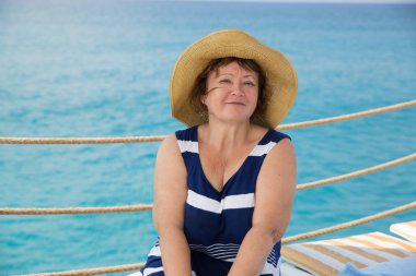 Gülümseyen kıdemli kadın kumsalda şapka