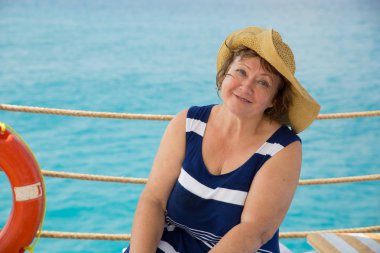 Gülümseyen kıdemli kadın kumsalda şapka