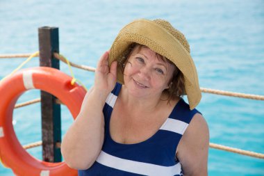 Gülümseyen kıdemli kadın kumsalda şapka