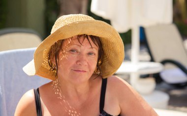 Gülümseyen kıdemli kadın kumsalda şapka