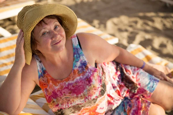 Smiling old woman at beach on sunbed — Stock Photo, Image