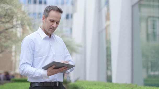 Homem de negócios digita em seu tablet digital — Vídeo de Stock