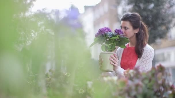 Jonge vrouw pakt een pot met bloemen — Stockvideo