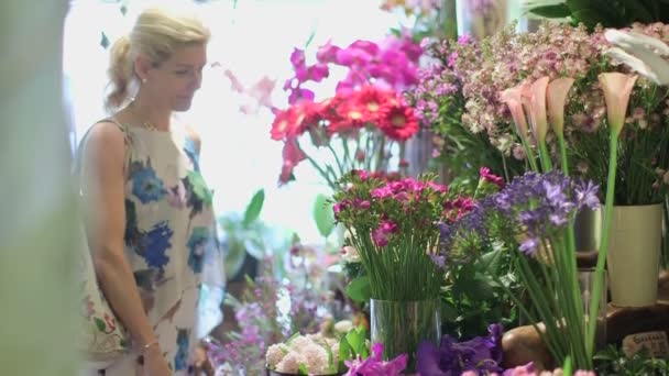 Μια γυναίκα Μυρίζοντας ομάδα στο πίνακα των λουλουδιών — Αρχείο Βίντεο
