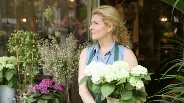 Ein Blumenhändler mit einem großen Topf voller Blumen — Stockvideo