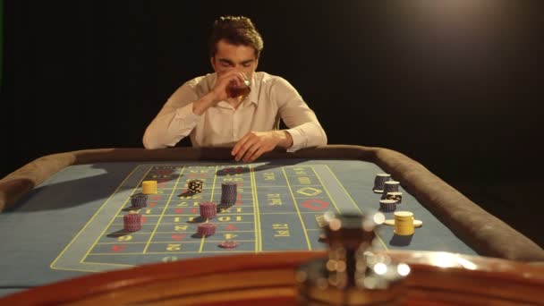 Человек потягивает свой напиток в казино — стоковое видео