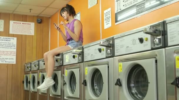 Kvinna sitter ovanpå en tvättmaskin — Stockvideo