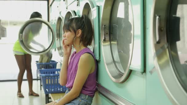 Woman with her smartphone in a Launderette — Stock Video