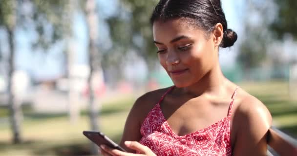 Menina sentado no parque e usando smartphone — Vídeo de Stock