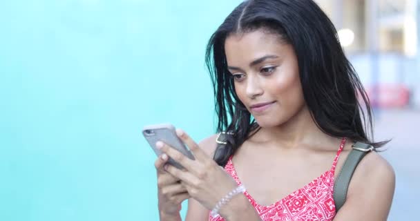 Chica joven usando teléfono inteligente y sonriendo — Vídeos de Stock