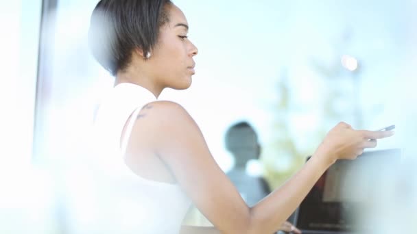 Zakenvrouw praten door de smartphone tijdens het werken op de laptop — Stockvideo