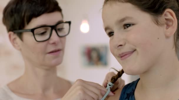 Мама заплетает дочери волосы — стоковое видео