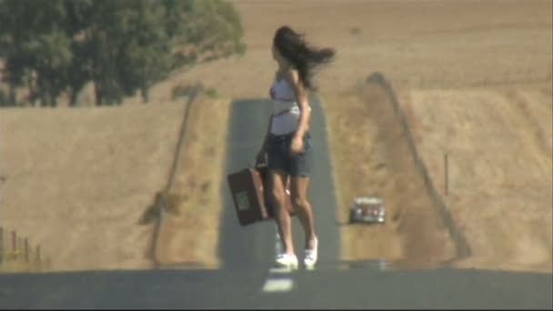 Uma jovem mulher carregando uma mala — Vídeo de Stock