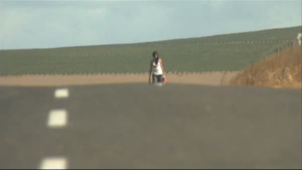 Mladá žena chůze po silnici — Stock video