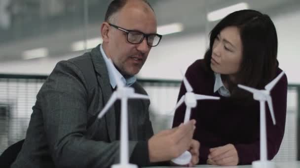Empresários que examinam modelos de turbinas eólicas — Vídeo de Stock