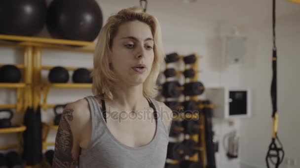 Jeune femme avec des tatouages levant des poids — Video