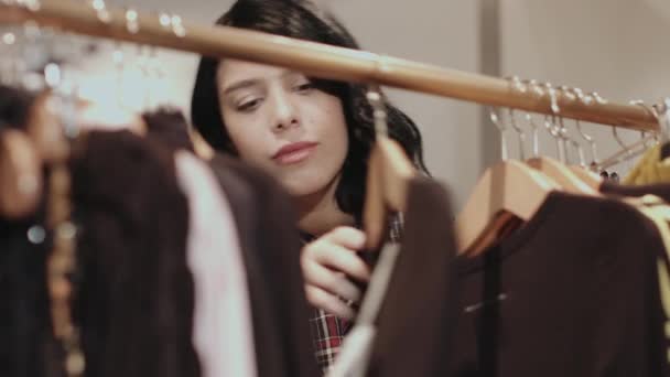 Молода доросла жінка дивиться на одяг — стокове відео