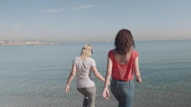 Deniz kenarında yürüyen kadınlar