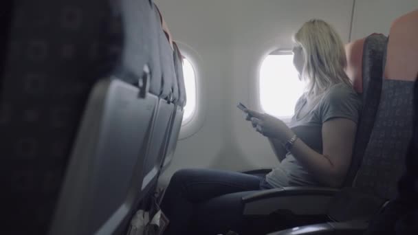 Weibchen im Flugzeug mit Telefon — Stockvideo