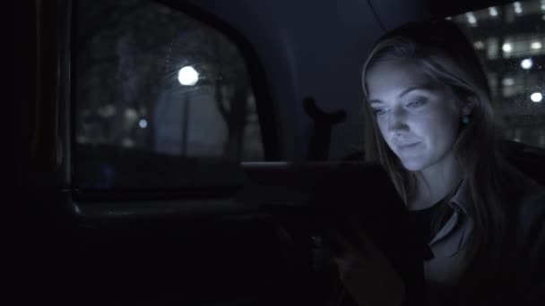 Ung kvinna i taxi med surfplatta — Stockvideo